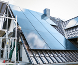 Person installing solar panels at the construction site of a house